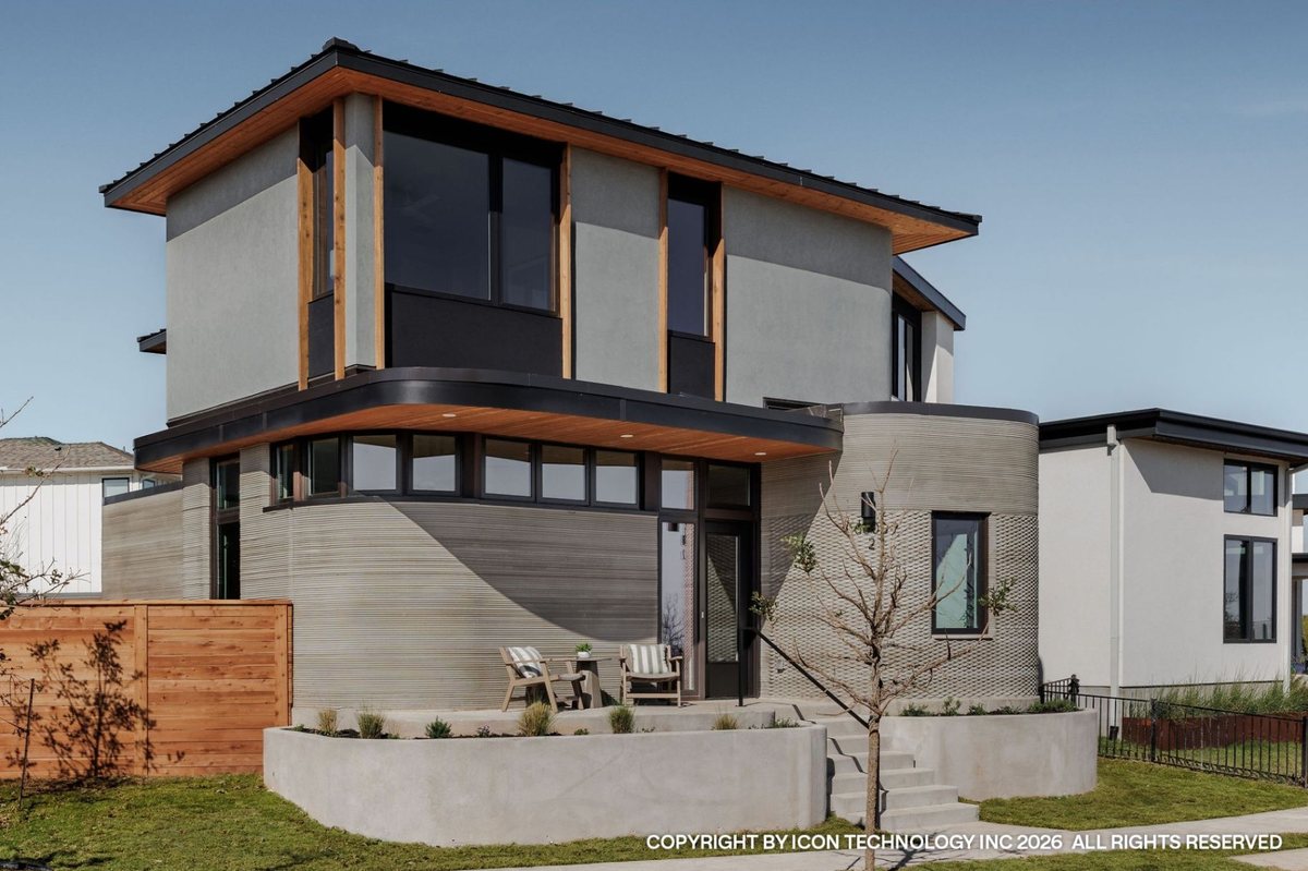 A two-story ICON-printed concrete home with printed textured walls, timber accents and a raised planted entry court, with adjacent homes in the background.